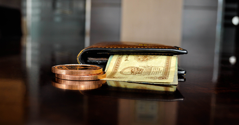 Wallet with paper money sandwiched and coins on desk